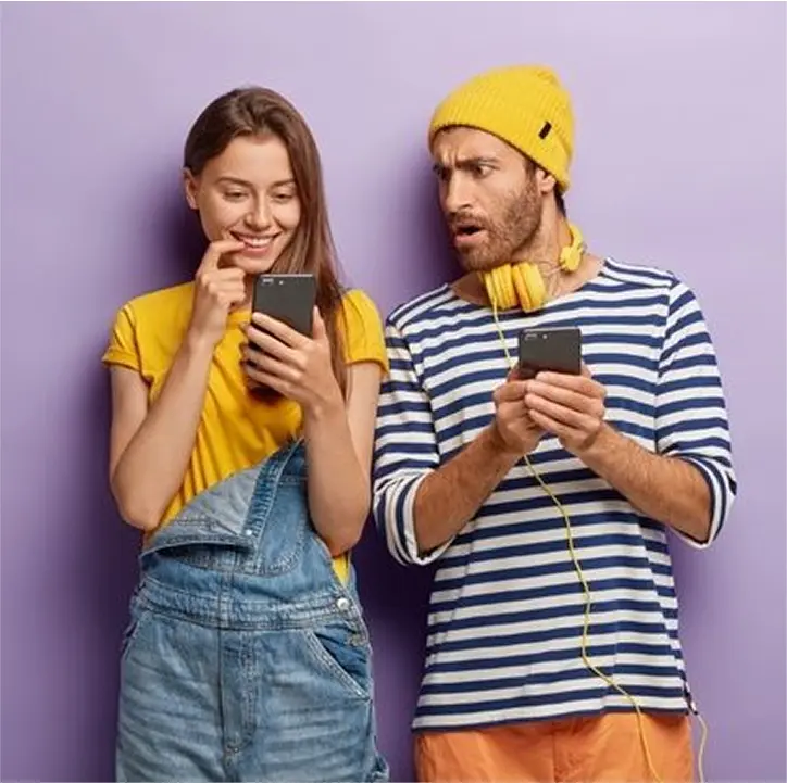 Изображение счастливая девушка и удивленный парень с телефонами в руках